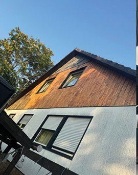 Stark verwitterte, ungepflegte Holzverschalung am Dachgiebel vor den Arbeiten